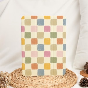 Puede incluir: Una funda para tableta con un colorido patrón de tablero de ajedrez. La funda presenta un fondo crema con cuadrados en tonos de amarillo, rosa, verde, azul y naranja. La funda rectangular parece estar hecha de un material duradero.