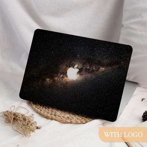 Può includere: Una skin per laptop con una stampa ad alta risoluzione della galassia della Via Lattea su sfondo nero profondo, stelle bianche sparse e una nebulosa dorata centrale. Il design include un ritaglio preciso per il logo Apple centrale.