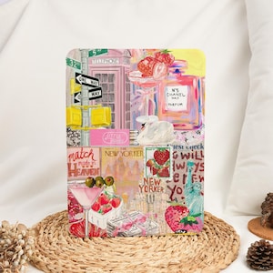 Op de afbeelding: Een rechthoekige kunstprint met een collage van New York City-beelden. Het bevat een roze telefooncel, straatnaamborden, aardbeien, een parfumfles en teksten zoals "The New Yorker" en "Match Made in Heaven".