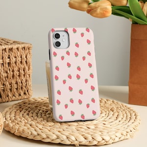 Könnte beinhalten: Eine rosa Handyhülle mit einem sich wiederholenden Muster aus roten Erdbeeren. Die Hülle ist für ein iPhone mit einem Kameraausschnitt konzipiert.