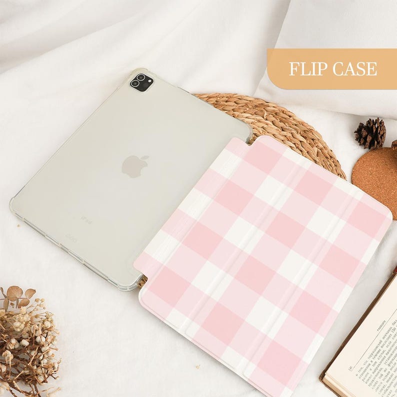 Pu&ograve; includere: Un iPad trasparente con una custodia a ribalta a quadri rosa e bianchi. La custodia &egrave; aperta, rivelando lo schermo. Il testo "FLIP CASE" &egrave; in un rettangolo beige sullo sfondo. L'iPad &egrave; su una superficie bianca.