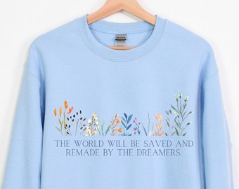 May include: Light blue sweatshirt with a floral design and the text "The world will be saved and remade by the dreamers."