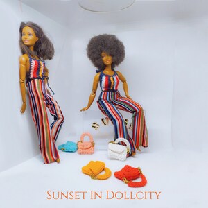 Könnte beinhalten: Zwei Modepuppen in bunten gestreiften Jumpsuits mit Häkeltops. Mehrere Miniatur-Häkeltaschen in verschiedenen Farben, darunter Orange, Rosa und Weiß, sind ausgestellt. Der Text "SUNSET IN DOLLCITY" befindet sich unten.