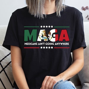 May include: Black t-shirt with the word "MAGA" in green and red, with the Mexican flag incorporated into the design. The text "MEXICANS AIN'T GOING ANYWHERE" is below the word "MAGA".