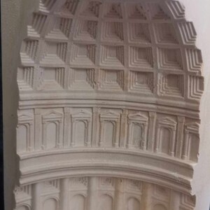 May include: A white plaster model of a building with a dome and columns. The model is carved with intricate details, including a grid pattern on the dome and arches around the columns.