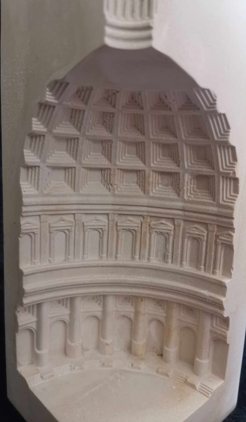May include: A white plaster model of a building with a dome and columns. The model is carved with intricate details, including a grid pattern on the dome and arches around the columns.