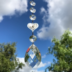 May include: A crystal suncatcher with a heart-shaped charm and a teardrop-shaped crystal hanging from a chain.