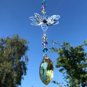 May include: A silver butterfly-shaped suncatcher with a crystal teardrop hanging from it. The butterfly has a beaded chain with colourful crystals in shades of blue, green, purple, and yellow.