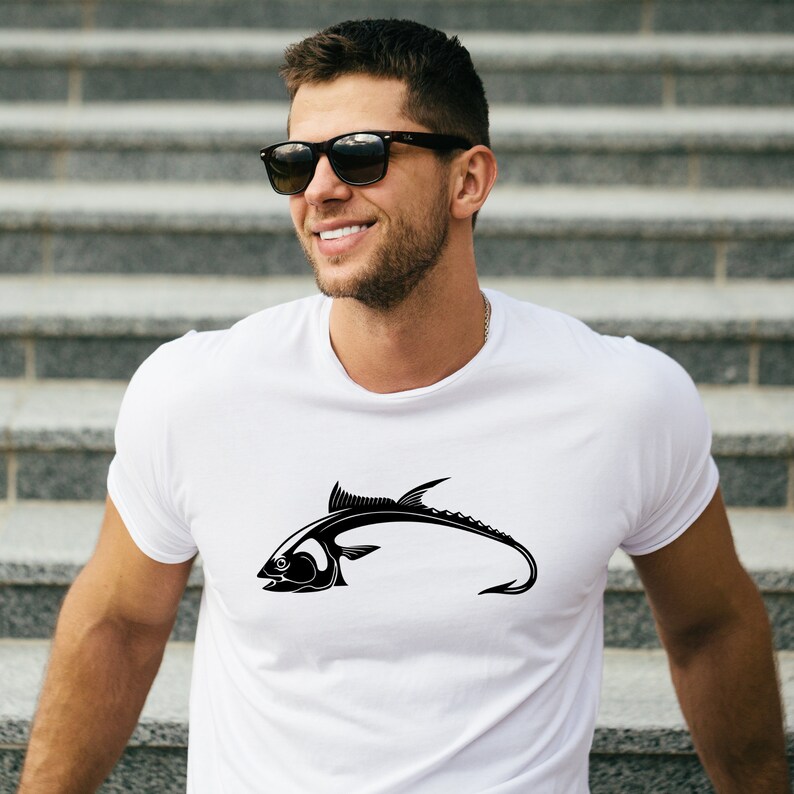 May include: White t-shirt with a black silhouette of a fish with a hook in its mouth.