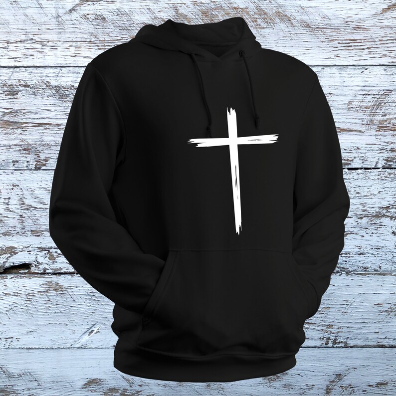 May include: Black hooded sweatshirt with a white distressed cross graphic on the front.