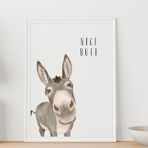 May include: Watercolor print of a donkey with the text "NICE BUTT" in black. The donkey is gray and white, with large ears and a friendly expression. The print is in a white frame.