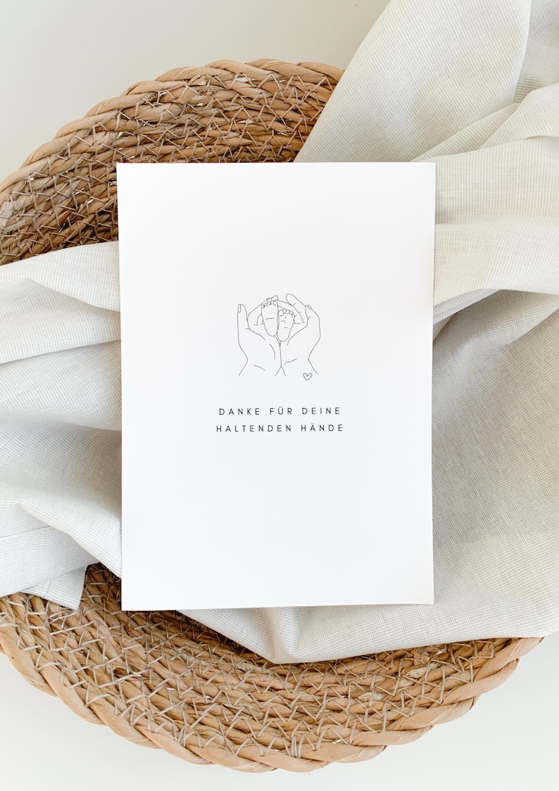 May include: A white card with a line drawing of two hands holding a pair of baby feet. The text "DANKE F&Uuml;R DEINE HALTENDEN H&Auml;NDE" is printed below the drawing.