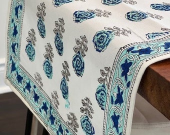 May include: White table runner with a blue and green floral pattern. The runner has a decorative border with a blue and green floral design.