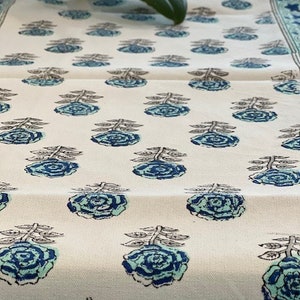 May include: White table runner with a repeating pattern of blue and green floral designs. The flowers are stylized and have a vintage look.