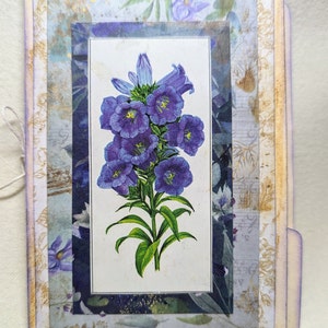 May include: A vintage card with a layered design featuring a purple flower illustration. The card has a distressed, aged look with a light brown background and a white border.