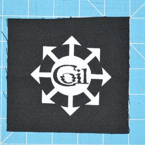 May include: Black fabric patch with a white eight-pointed star design and the word "Gil" in the center.