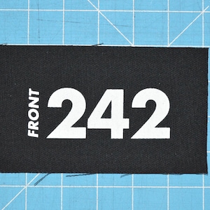 May include: Black fabric patch with white text that reads "FRONT 242".