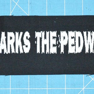 May include: Black fabric patch with white text that reads "X Marks The Pedwalk".