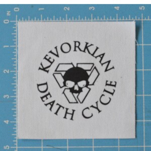 May include: White fabric patch with black text and a skull graphic. The text reads "Kevorkian Death Cycle".