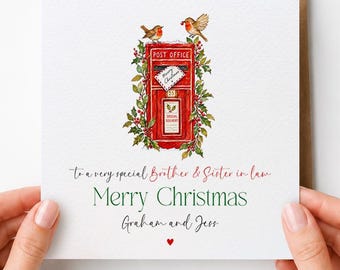 May include: A square white greeting card featuring a watercolor illustration of a red British post office box surrounded by holly and two robins. The text reads: To a very special Brother & Sister in law, Merry Christmas, Graham and Jess.
