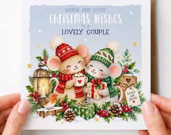 May include: A square greeting card featuring two illustrated mice wearing winter hats and scarves. One mouse holds a mug, the other a gift. Text reads: WARM AND COSY CHRISTMAS WISHES TO A LOVELY COUPLE. Includes a lantern, robin, and greenery.