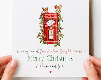 May include: A square white greeting card featuring a red British post box illustration surrounded by holly and two robins. The text reads: To a very special Son & future Daughter in law, Merry Christmas, Graham and Jess, with a small red heart.