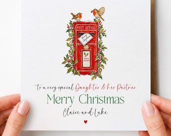 May include: A square greeting card featuring a watercolor illustration of a red post box surrounded by holly and two robins. The text reads: To a very special Daughter & her Partner, Merry Christmas, Claire and Luke, with a small red heart.