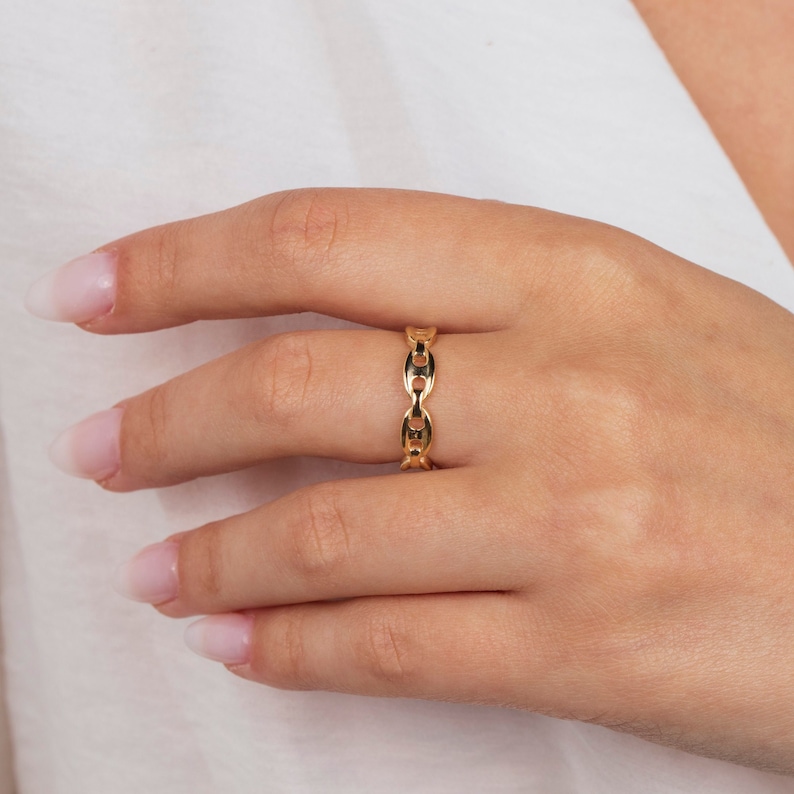 K&ouml;nnte beinhalten: Ein goldener Kettenring mit schlichtem Design. Der Ring besteht aus einer dicken, massiven Kette und ist ein Statement-Piece.