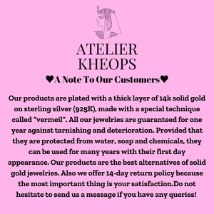 K&ouml;nnte beinhalten: Ein rosa Hintergrund mit einer Schwarzwei&szlig;illustration eines &auml;gyptischen Frauenkopfes. Der Text "ATELIER KHEOPS" ist in Schwarzwei&szlig;. Der Text "A Note To Our Customers" ist in Schwarzwei&szlig; mit einem rosa Herzen auf jeder Seite. Der Text darunter erkl&auml;rt, dass die Produkte mit einer dicken Schicht 14 Karat Gold auf Sterlingsilber plattiert sind und ein Jahr lang gegen Anlaufen und Abnutzung garantiert sind.