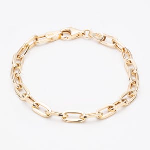 May include: A 14K yellow gold chain bracelet featuring elongated oval links connected in a continuous loop. The bracelet includes a secure lobster claw clasp mechanism, with the 14K hallmark clearly stamped on the metal surface near the closure.