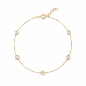 May include: A delicate gold bracelet featuring five round, clear gemstones evenly spaced along a fine chain. The bracelet has a lobster clasp closure and an adjustable chain for a comfortable fit. The gemstones are set in a bezel setting.