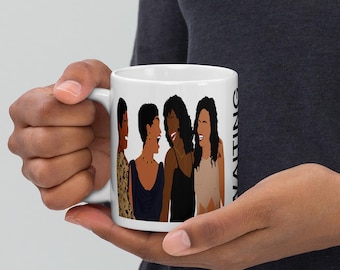 May include: White ceramic mug featuring a graphic of four women in various outfits, laughing. The mug has the word "WAITING" printed vertically on the side. The women are depicted with different skin tones and hairstyles.