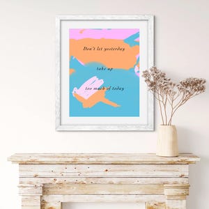 May include: A framed print with a blue, pink, and orange abstract background. The text "Don't let yesterday take up too much of today" is printed in black on the print.