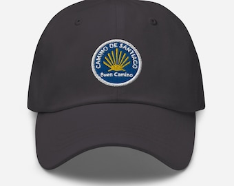 Può includere: Un cappello da baseball nero con una toppa ricamata che presenta una conchiglia di capesante e il testo "Camino de Santiago" e "Buen Camino".