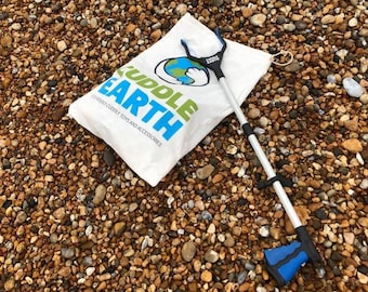 Może przedstawiać: Biała torba z napisem "Cuddle Earth" i grafiką niebieskiej i zielonej kuli ziemskiej. Na torbie leży niebieski i srebrny chwytak. Torba i chwytak znajdują się na łóżku z małych brązowych i beżowych kamyków.