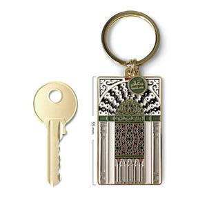 May include: A gold-toned metal keyring featuring a rectangular pendant with an intricate architectural arch design in green, black and white enamel. A small circular tag reads "malam". A key is shown for scale, indicating a height of 55 mm.