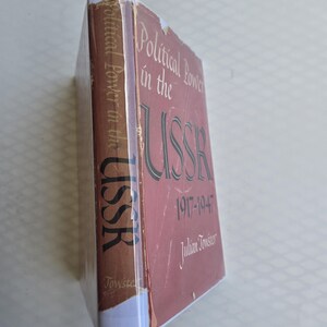 May include: A hardcover book titled "Political Power in the USSR 1917-1947" by Julian Towster. The book has a red cover with white and black lettering. The spine is brown with white text. The book is wrapped in clear plastic.