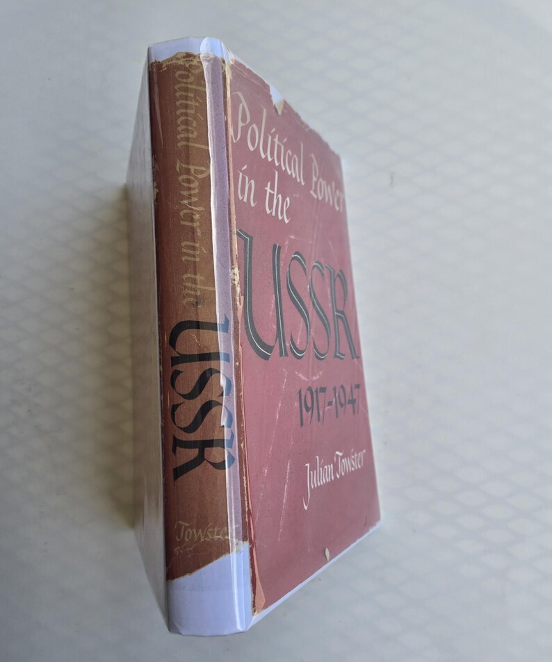 May include: A hardcover book titled "Political Power in the USSR 1917-1947" by Julian Towster. The book has a red cover with white and black lettering. The spine is brown with white text. The book is wrapped in clear plastic.