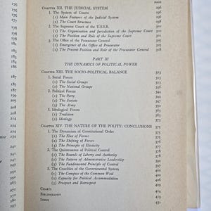 May include: Open book with a table of contents and page numbers. The text includes chapter titles such as "The Judicial System" and "The Dynamics of Political Power." The pages are yellowed with age.