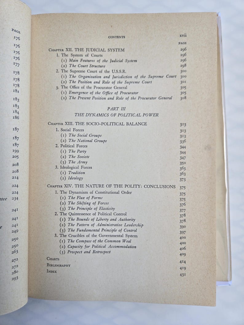May include: Open book with a table of contents and page numbers. The text includes chapter titles such as "The Judicial System" and "The Dynamics of Political Power." The pages are yellowed with age.