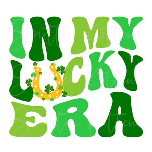May include: Green and yellow graphic with the text "In My Lucky Era" in a retro font. A gold horseshoe with shamrocks is in the center of the graphic.