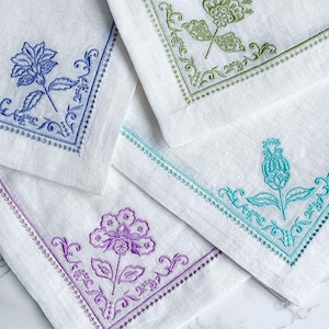 Servilletas de lino blanco para cena de Mary DiSomma con bordado floral, dobladillo y ribete de ojales en azul, verde azulado, verde musgo y lavanda / Juego de 4