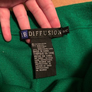 Może przedstawiać: Czarna metka pielęgnacyjna z białym tekstem, który brzmi: "1.B. DIFFUSION 70% ACRYLIC/ACRYLIQUE/ACRILICA 30% WOOL/LAINE/LANA MADE IN CHINA FABRIQUE EN CHINE HECHO EN CHINA RN 46561 CA 00184 CARE INSTRUCTIONS ON REVERSE SIDE INSTRUCTIONS DE LAVAGE AU VERSO INSTRUCCIONES AL REVERSO"