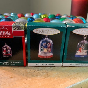 May include: Three Hallmark Keepsake Ornament boxes with a red, green, and blue background. The boxes feature a clear glass dome with a miniature figurine inside. The boxes are labeled with the years 1993, 1994, and 1991. The boxes are part of a New Collector's Series called The Bearymores.