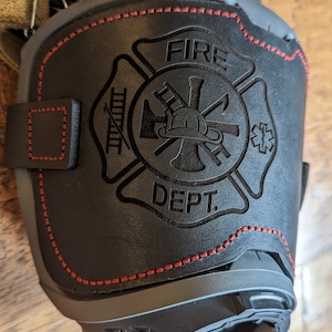 May include: Black leather fire department patch with red stitching. The patch features a firefighter's helmet, axe, ladder, and the words "FIRE DEPT."