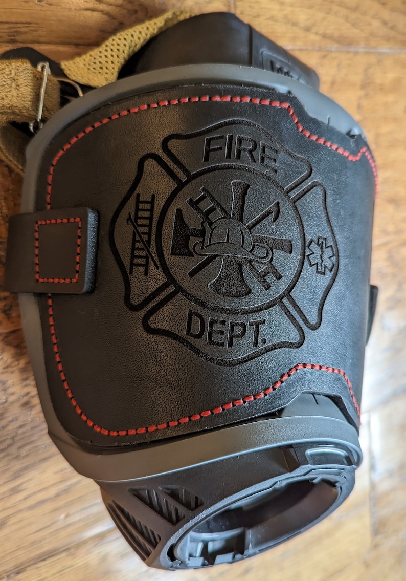 May include: Black leather fire department patch with red stitching. The patch features a firefighter's helmet, axe, ladder, and the words "FIRE DEPT."