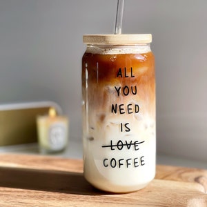 May include: A glass jar with a bamboo lid and a glass straw filled with iced coffee. The jar has the text "All you need is love coffee" printed on it.