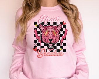 May include: Pink sweatshirt with a graphic of a pink leopard with heart-shaped eyes and the text "Heart Breaker" in a retro font.