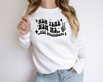 May include: White sweatshirt with a black graphic that reads "New Year New Me...ntal breakdowns" with a lightning bolt and a peace sign.