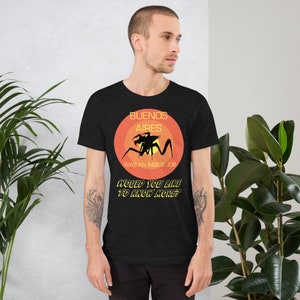 May include: A black t-shirt with a graphic of a creature with the text "Buenos Aires Was An Inside Job" and "Would You Like To Know More?"